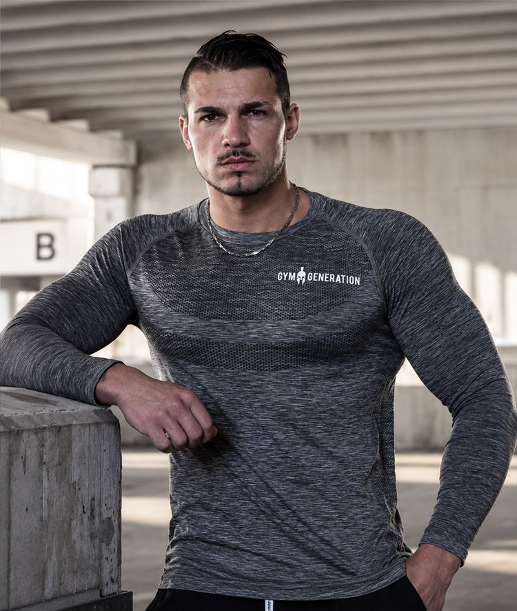 Seamless Longsleeve Herren Dunkelgrau am Model in urbaner Betonkulisse, eng anliegend mit Lochstruktur über der Brust