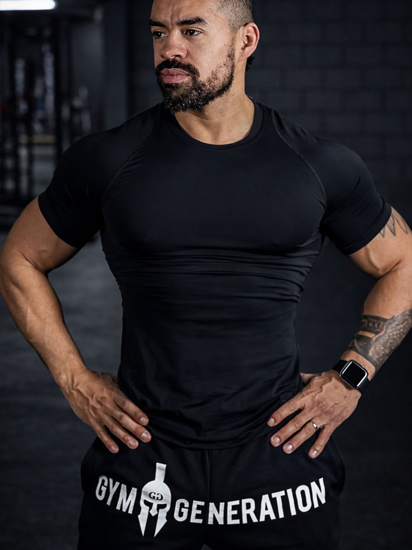 Athlet trägt Gym Generation Herren Trainerhose in Schwarz im Fitnessstudio, sportlicher Gym-Lifestyle mit Logo-Print in Trainingsumgebung