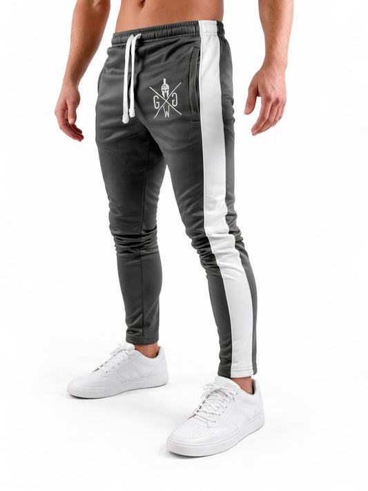 Seitliche Studioaufnahme der Gym Generation Herren Trainerhose in Dunkelgrau mit weißem Seitenstreifen und Logo, sportliche Trainingshose mit schmaler Passform