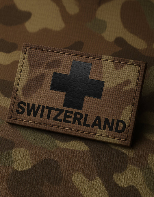 Swiss Military Patch SWITZERLAND aus PVC in Camouflage-Optik mit schwarzem Schweizer Kreuz, detailreich auf taktischem Tarnstoff fotografiert, Klett-Patch für Tactical Gear