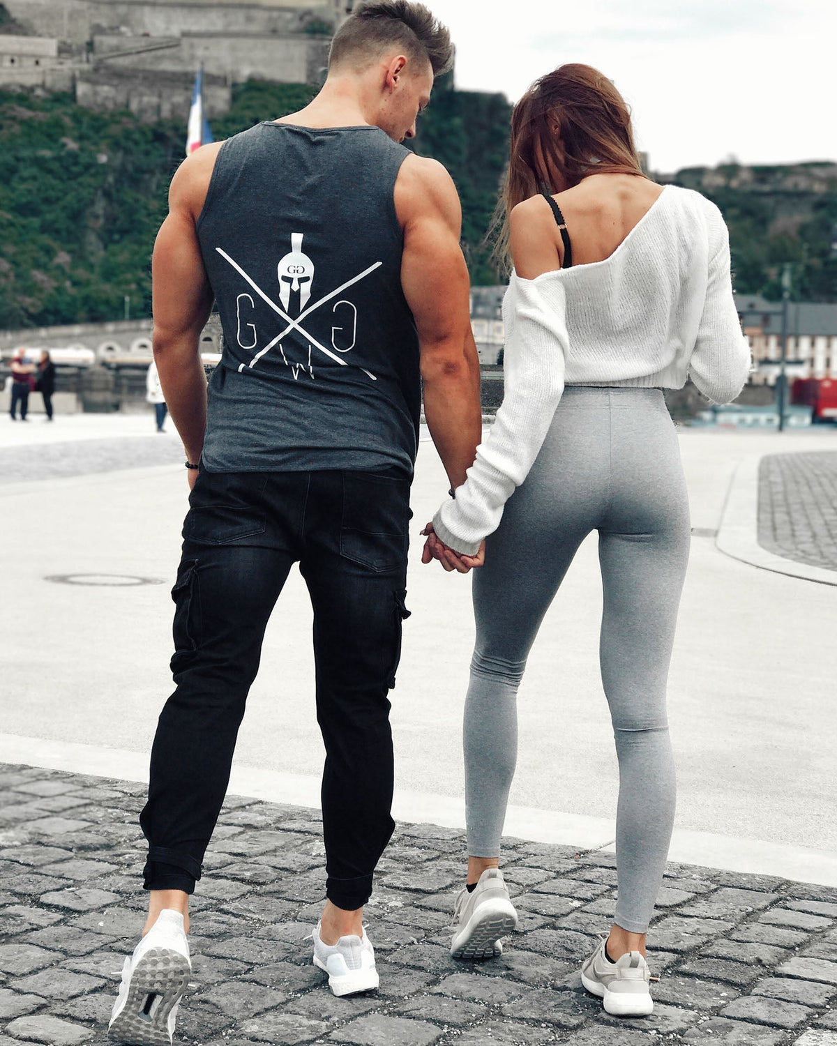 Couple holding hands, him in a Gym Generation tank top with Spartan logo on the back