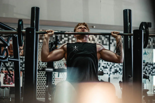 Athlet beim Bankdrücken im Fitnessstudio mit Gym Generation Tank Top – Krafttraining zur Muskelstimulation und Förderung der Muskelregeneration durch gezielte Belastung der Brust- und Schultermuskulatur.
