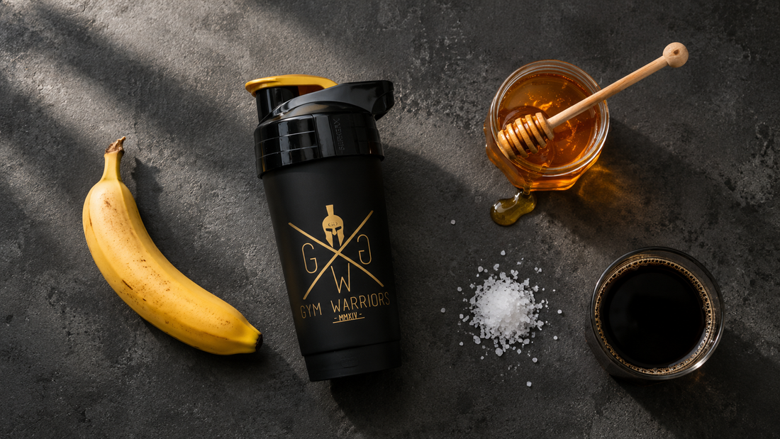 Gym Warriors Shaker mit Banane, Honig, Meersalz und schwarzem Kaffee als natürlicher Pre-Workout Booster auf dunklem Betonhintergrund.