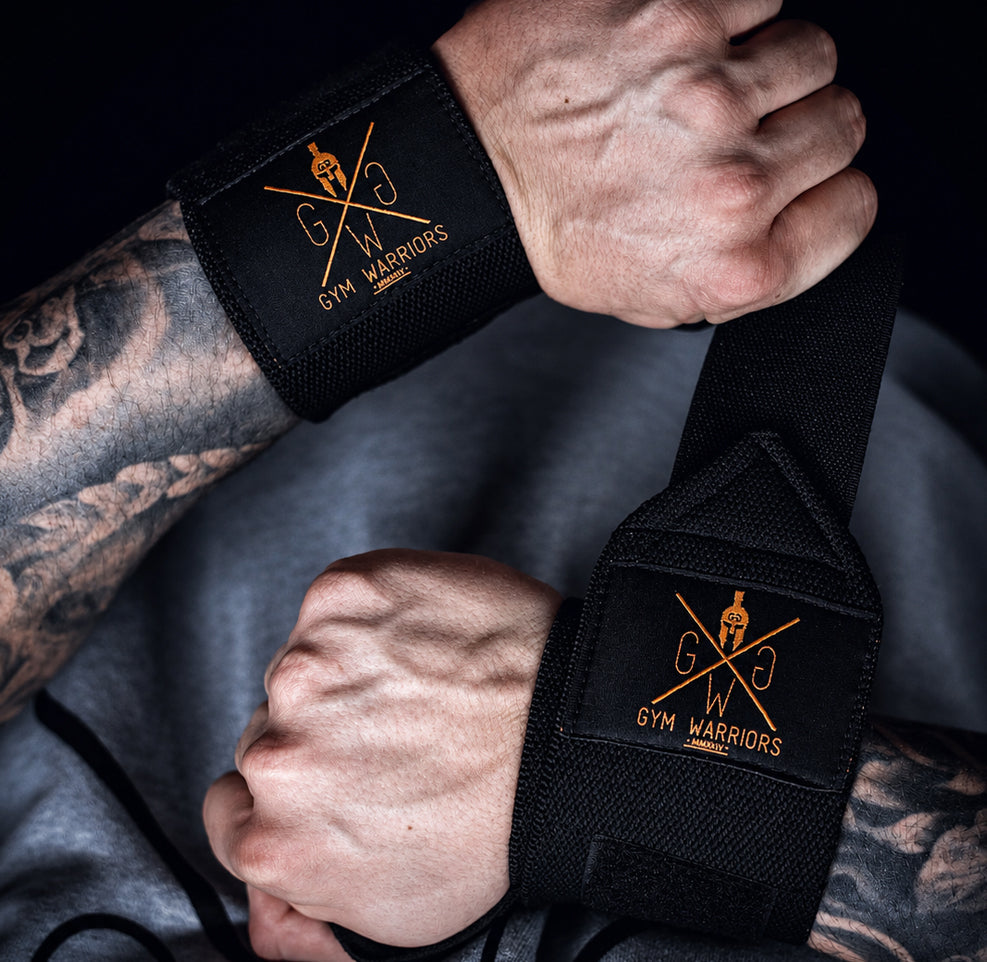 Athlet trägt schwarze Handgelenkbandagen mit Gym Warriors Logo beim Krafttraining – Gym Generation