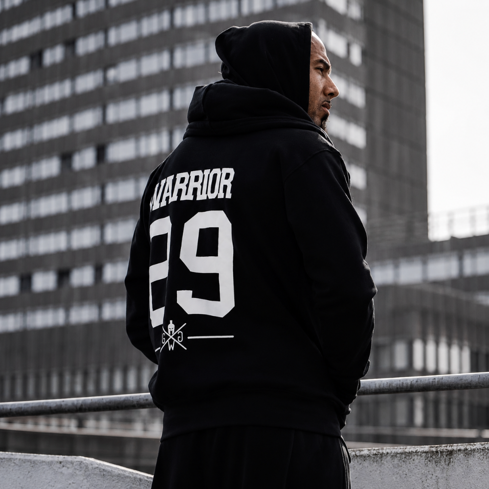 Schwarzer Gym Generation Warrior Hoodie mit grossem Backprint, getragen im urbanen Outdoor-Look – sportlicher Herren Hoodie für Gym, Streetwear und Alltag