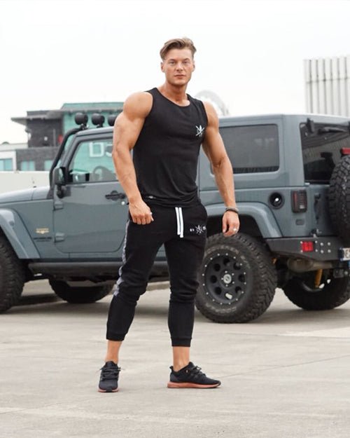 Mann trägt schwarze Gym Pants vor einem Jeep