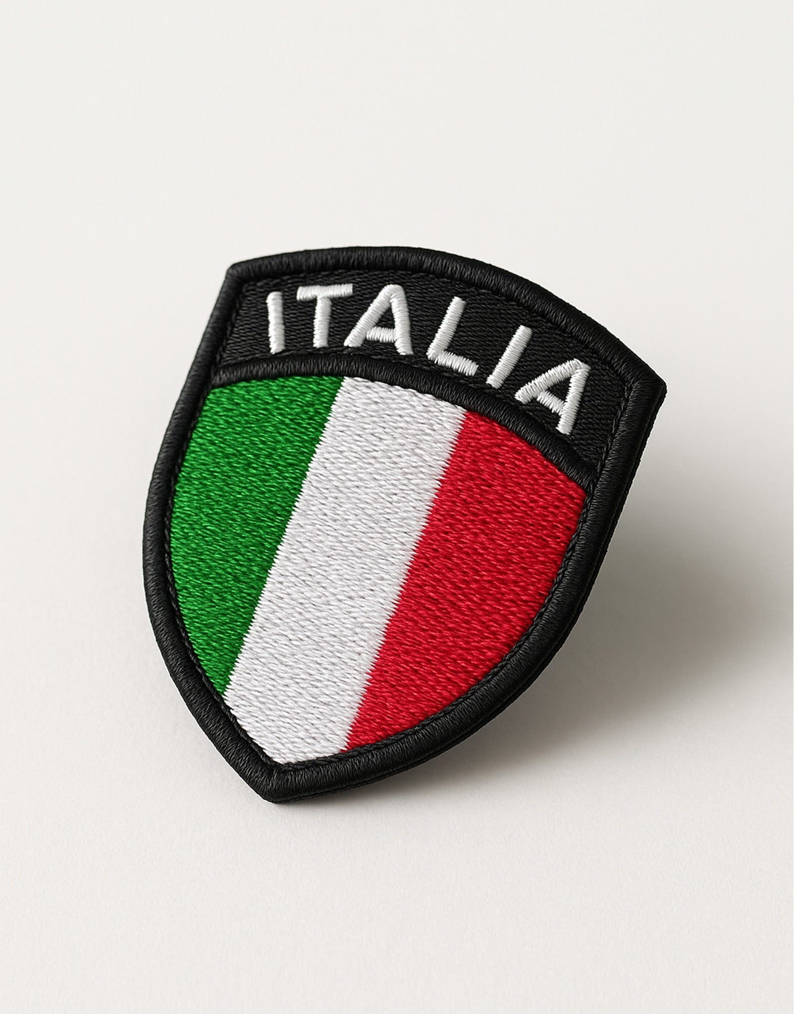 Detailaufnahme des Italien Tricolore Patches schräg positioniert, hochwertiger 3D-Stick, Wappenform mit Klettsystem, ideal zur Individualisierung von Sport-Equipment, Fan-Gear und Backpack-Customizing.