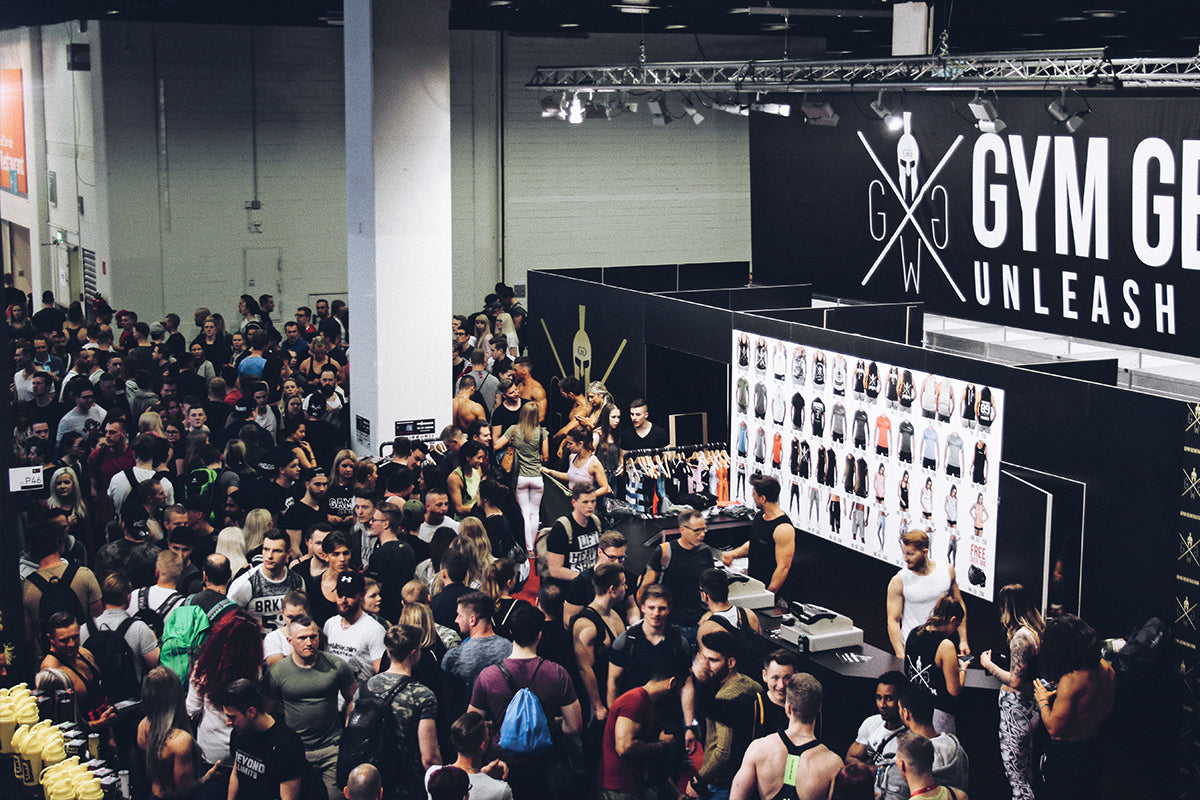 Großer Besucherandrang am Gym Generation Messestand auf einer Fitness-Expo, umgeben von Sportbekleidung, Marken-Branding und begeisterten Fitness-Fans, symbolisiert die starke Präsenz und Community-Bindung der Marke.