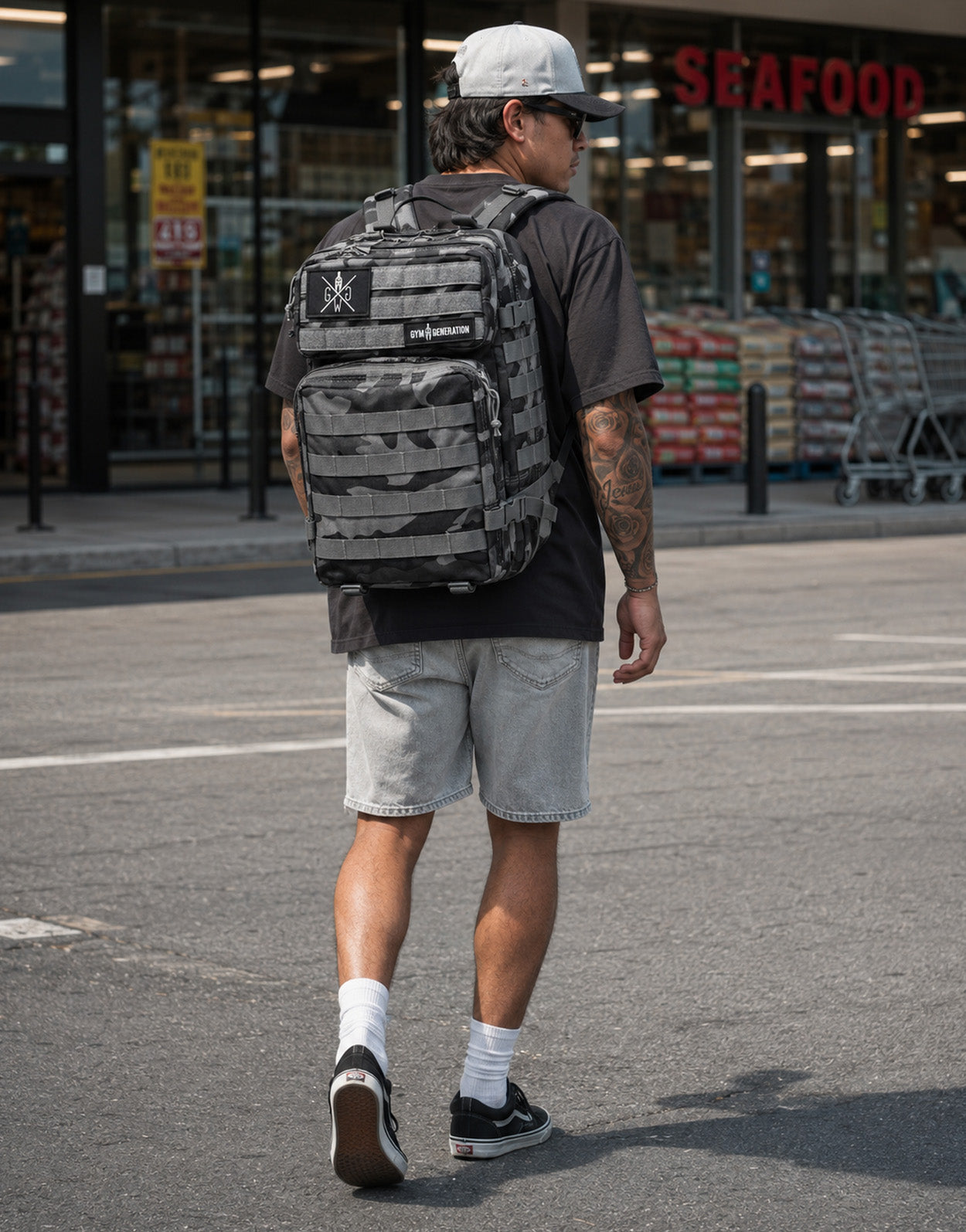 Gym Generation Fitness Rucksack in Grau Camo, getragen von Athlet vor Supermarkt im American Streetstyle mit Patches und MOLLE-System