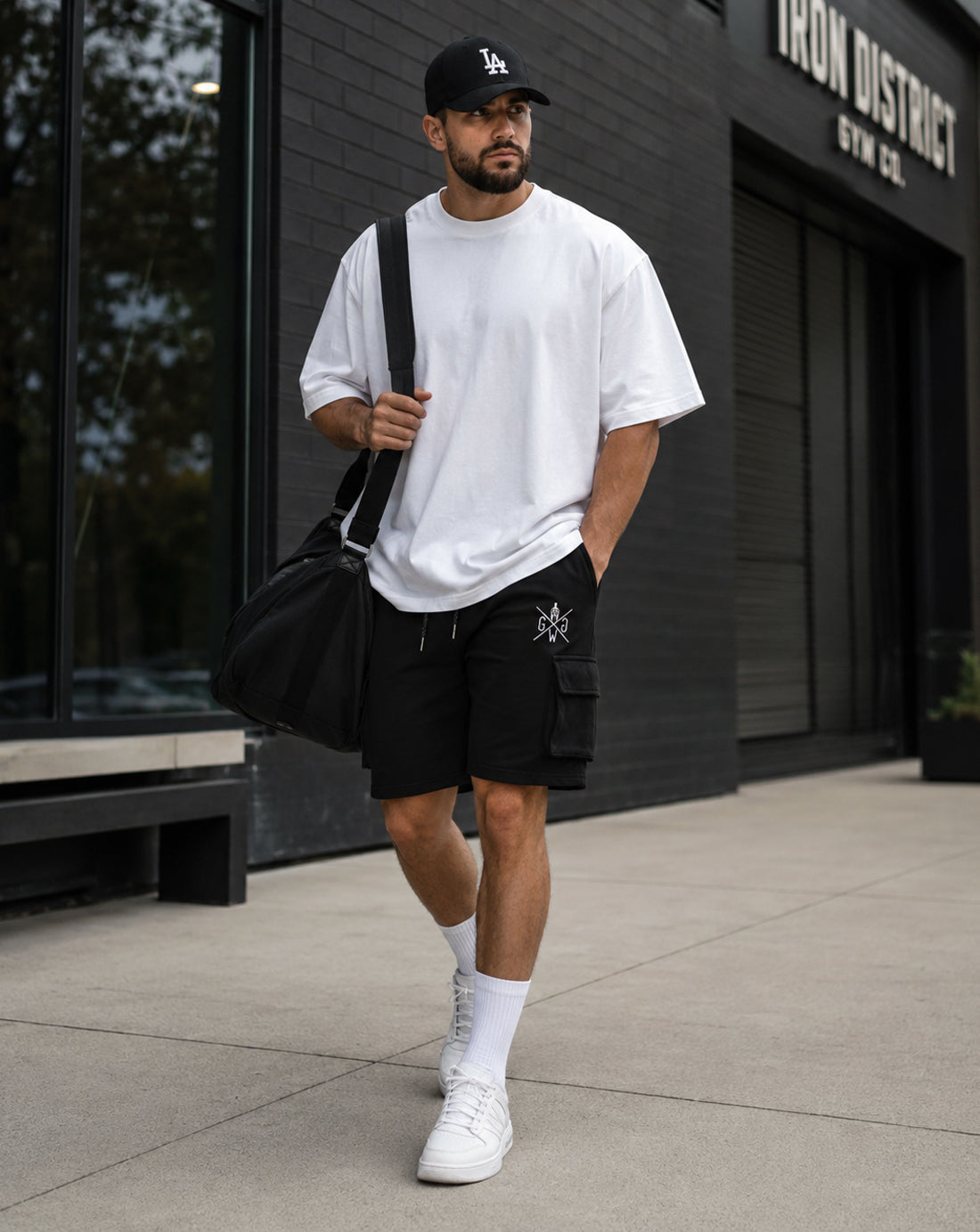 Gym Generation Maverick Cargo Gym Shorts Herren in Schwarz, getragen von Athlet Outdoor mit weissem Oversized Shirt, Cargo-Tasche und sportlichem Streetwear-Look