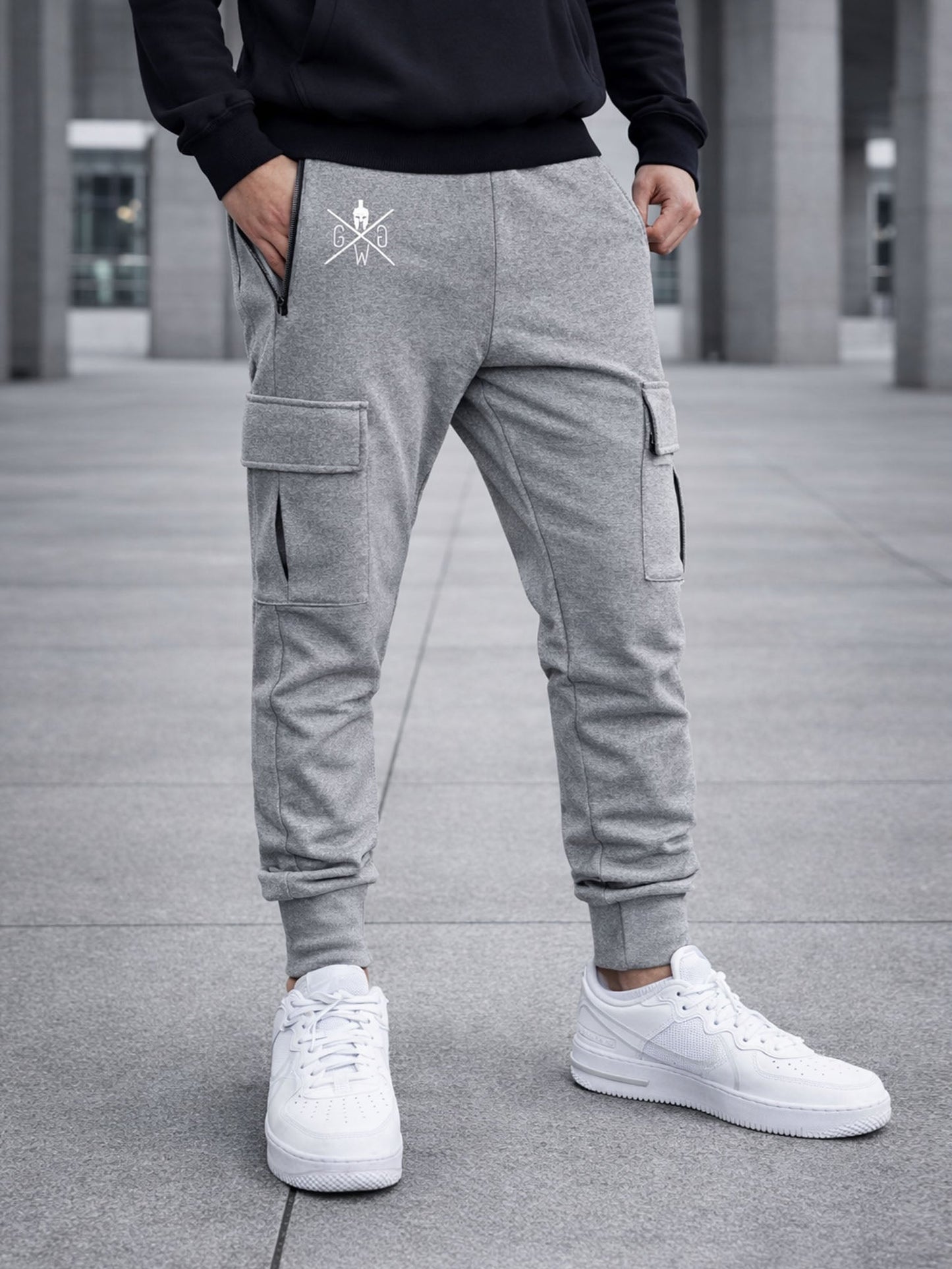 Graue Cargo Trainerhose für Herren von Gym Generation – urbanes Modellbild mit funktionalen Cargo-Taschen, Reissverschlussdetail und sportlichem Street-Style