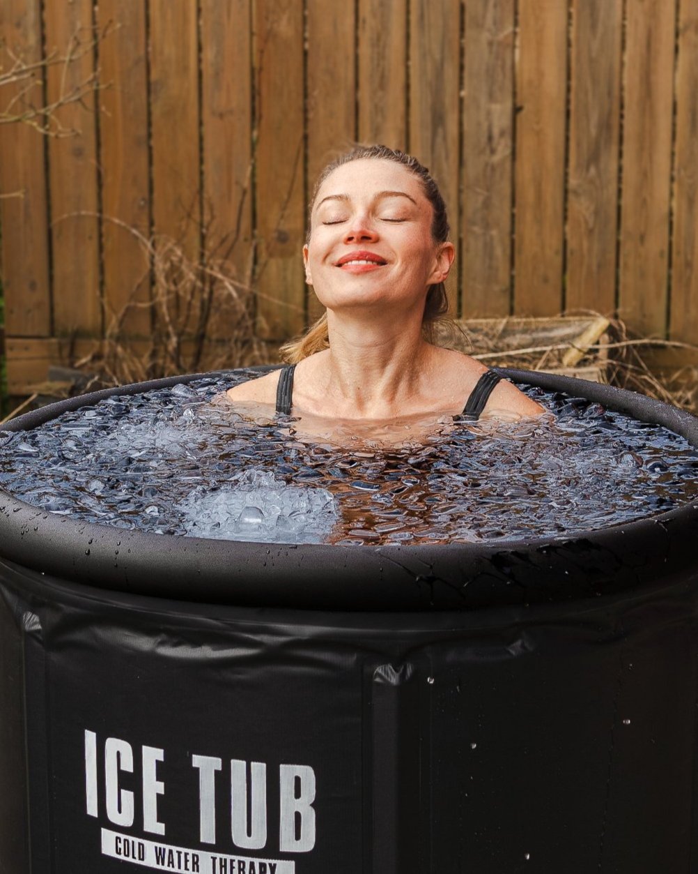 Frau entspannt sich in einer Eistonne gefüllt mit Eiswürfel und genießt die Kältetherapie, ideal für Stressabbau, Regeneration und Wohlbefinden.