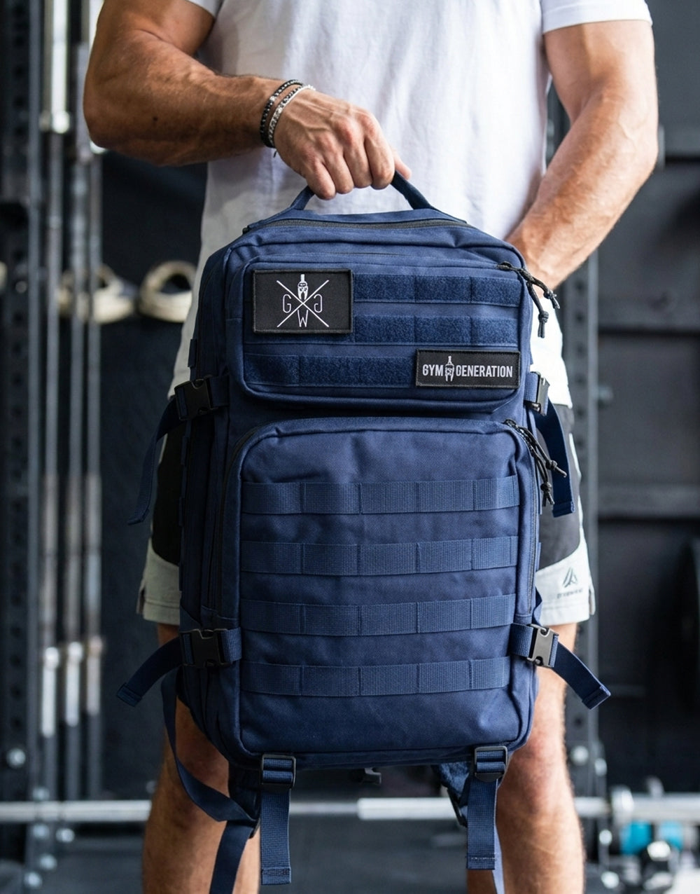 Gym Generation Fitness Rucksack Adventurer in Navy Blau, gehalten von Athlet im Gym mit MOLLE-System, Patches und robustem Trainingsdesign