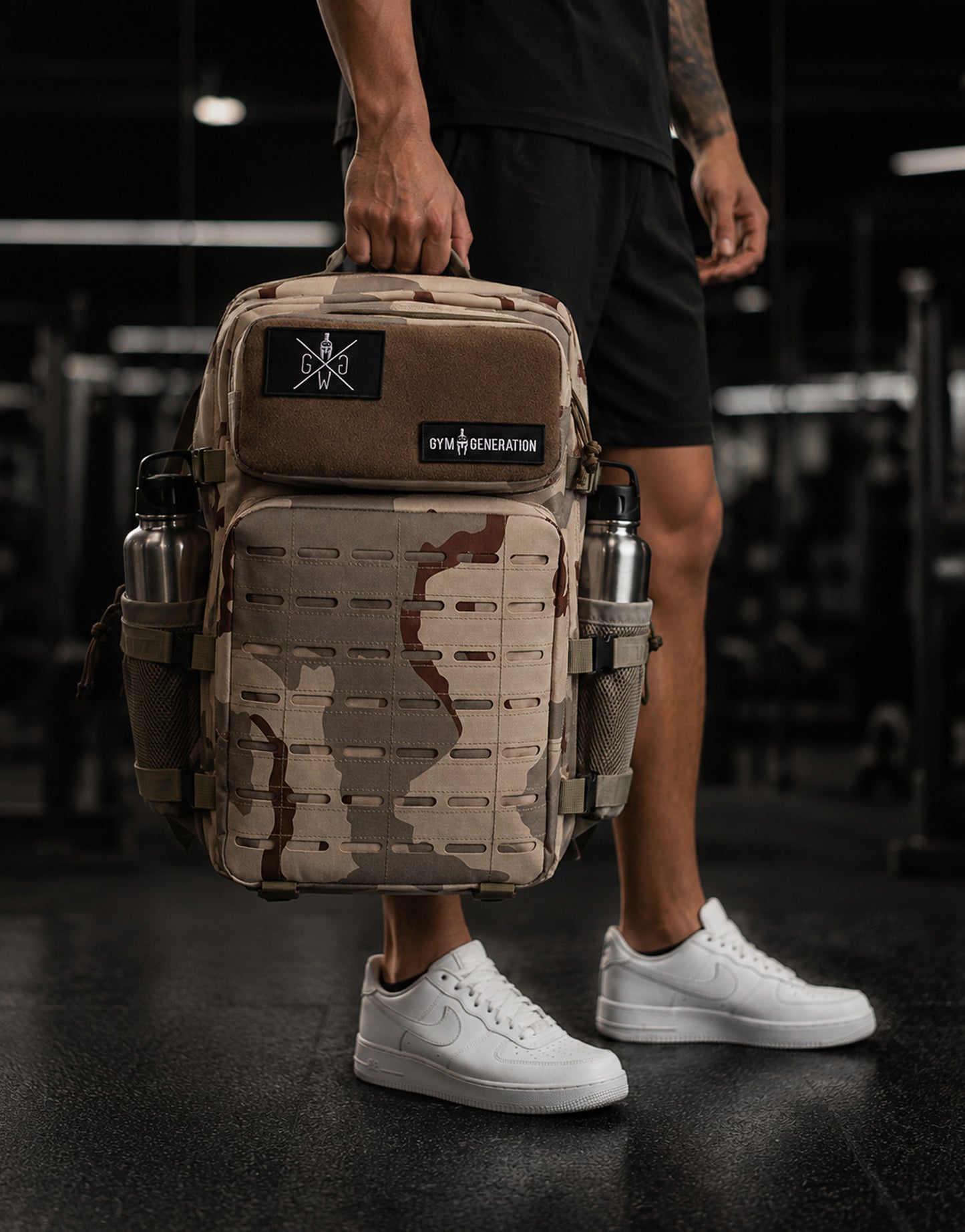 Gym Generation Fitness Rucksack Explorer in Desert Camo, von Athlet im Gym getragen mit Laser-Cut-MOLLE, Patches und seitlichen Flaschenfächern