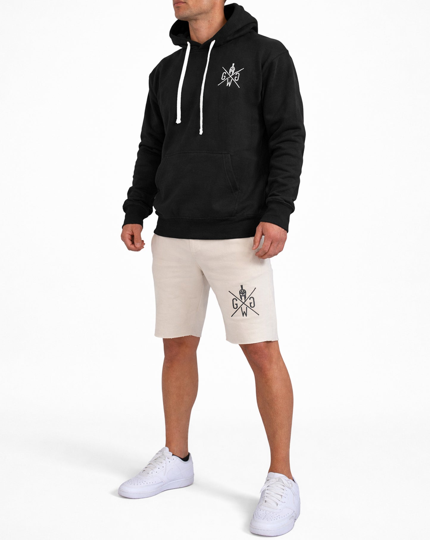 Beige Gym Shorts Herren von Gym Generation im Outfit – sportliche Fitness Shorts am Model kombiniert mit schwarzem Hoodie und Sneakers