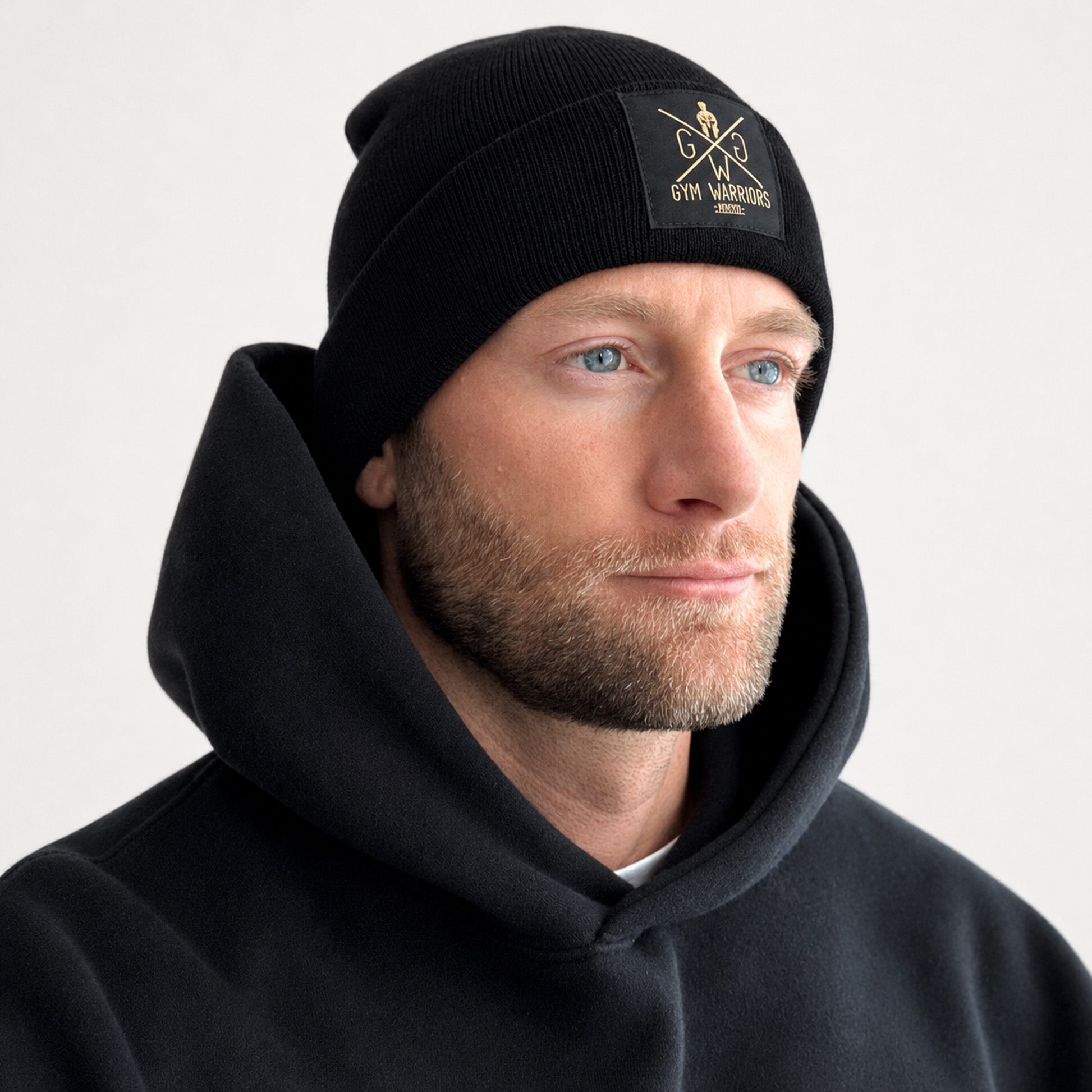 Gym Beanie Schwarz getragen – Gym Mütze mit goldenem Patch auf dem Umschlag von Gym Generation, Einheitsgrösse