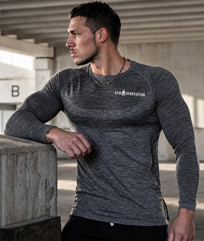 Langarm Sportshirt Herren Dunkelgrau am Model, seitlich an Betonmauer gelehnt, mit Raglanärmeln und Schriftzug in Weiss
