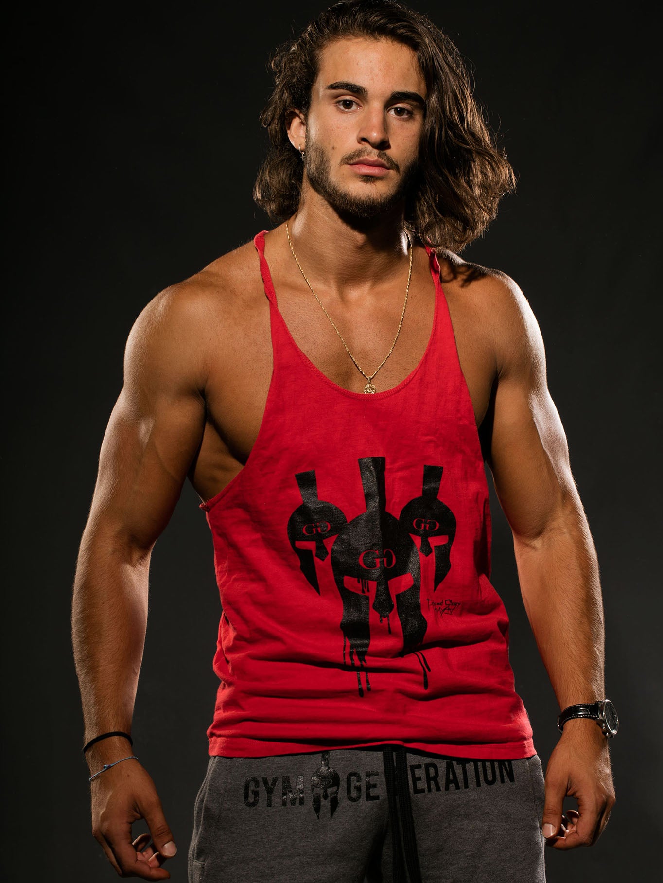 Athlet im roten Gym Generation Stringer Tank Top mit schwarzem Spartaner-Helm-Print und grauer Gym Generation Hose, ideal für intensives Training.