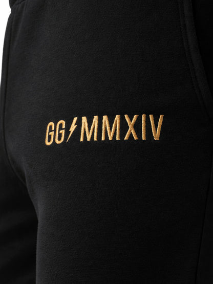 Detailaufnahme der Gym Generation Herren Trainerhose in Schwarz mit goldener GG MMXIV Stickerei, hochwertige Logo-Veredelung auf dem Stoff