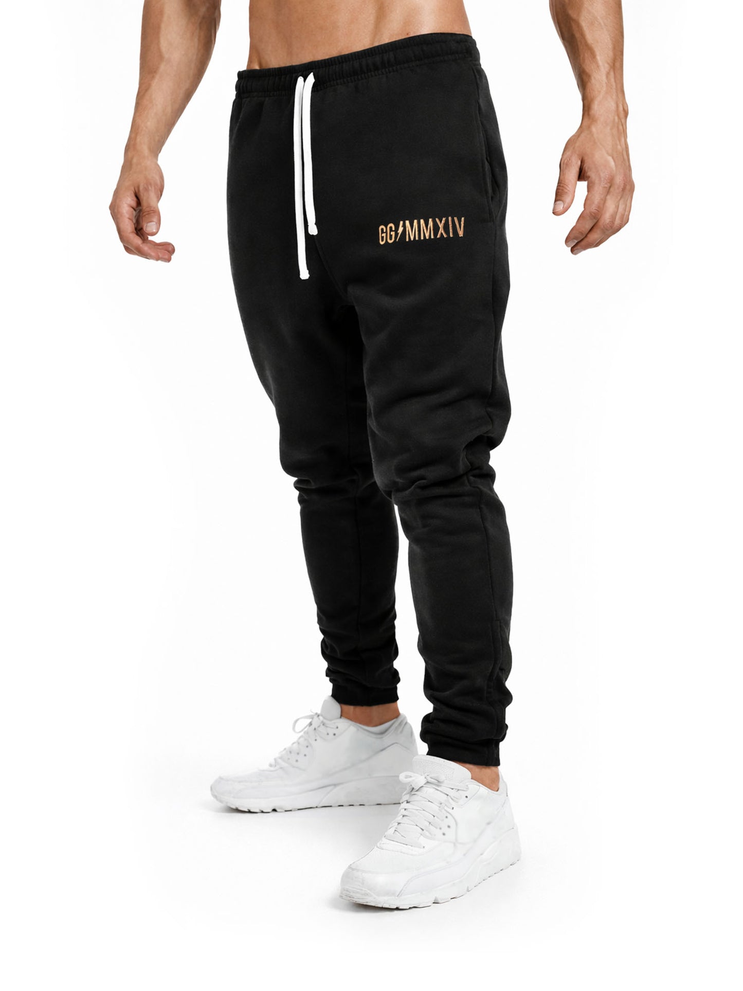 Seitliche Studioaufnahme der Gym Generation Herren Trainerhose in Schwarz mit goldener GG MMXIV Stickerei und Kordelzug, sportliche Trainingshose mit schmaler Passform