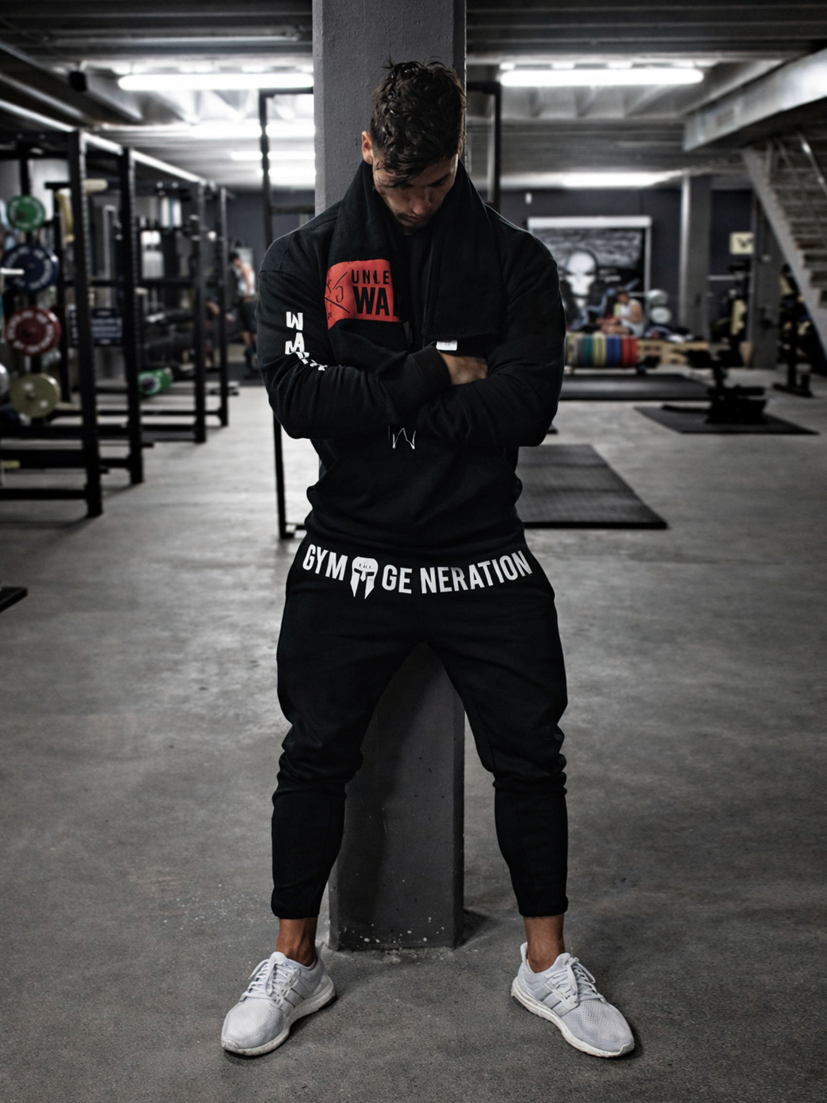 Athlet trägt Gym Generation Herren Trainerhose in Schwarz beim Training im Fitnessstudio, sportlicher Lifestyle-Look mit Logo-Print in aktiver Umgebung