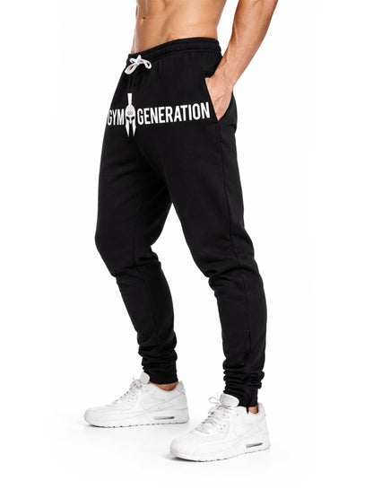Seitliche Studioaufnahme der Gym Generation Herren Trainerhose in Schwarz mit Logo-Print und Kordelzug, sportliche Trainingshose für Fitnessstudio und Krafttraining