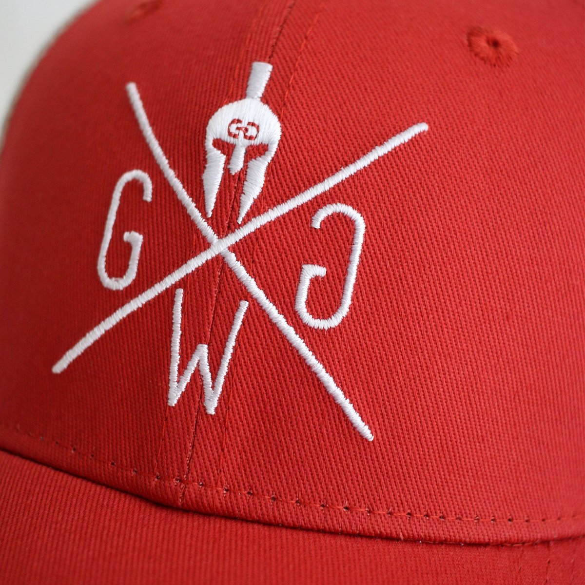 Nahaufnahme des gestickten Gym Generation Logos auf der Vorderseite des roten Gym Trucker Cap.