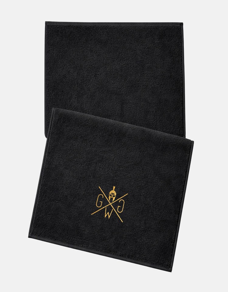 Schwarzes Fitness-Handtuch von Gym Generation mit goldenem Logo, Studio-Flatlay auf weissem Hintergrund.