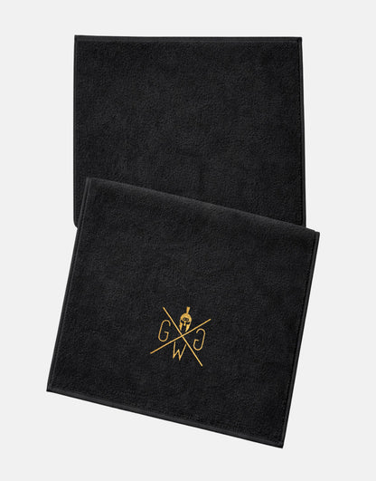 Schwarzes Fitness-Handtuch von Gym Generation mit goldenem Logo, Studio-Flatlay auf weissem Hintergrund.