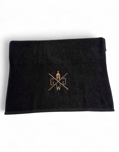 „Premium Fitnesshandtuch schwarz mit goldgesticktem Gym Generation Logo – hochwertige Verarbeitung, detailreicher Stoff.