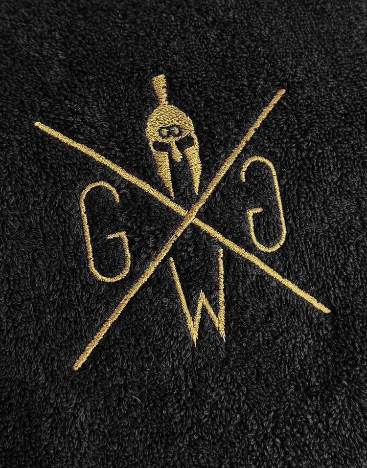 Nahaufnahme Sporthandtuch Schwarz mit goldenem Logo – edle Stickerei auf Baumwollstoff, Gym Handtuch von Gym Generation.