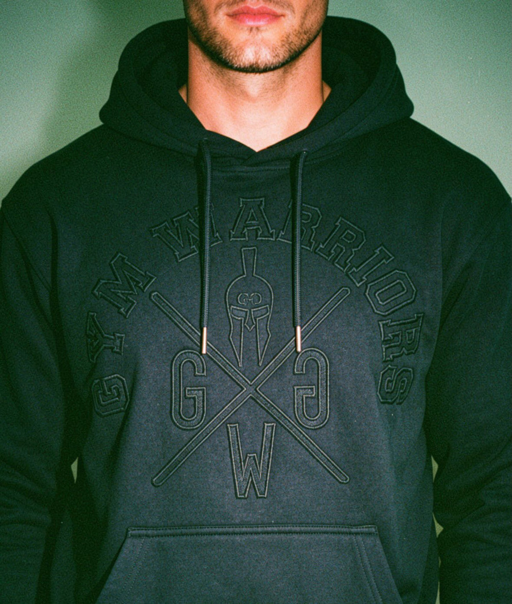 Athlet trägt schwarzen Gym Warriors Hoodie mit Ton-in-Ton Stickerei, Kapuze und sportlichem Fit