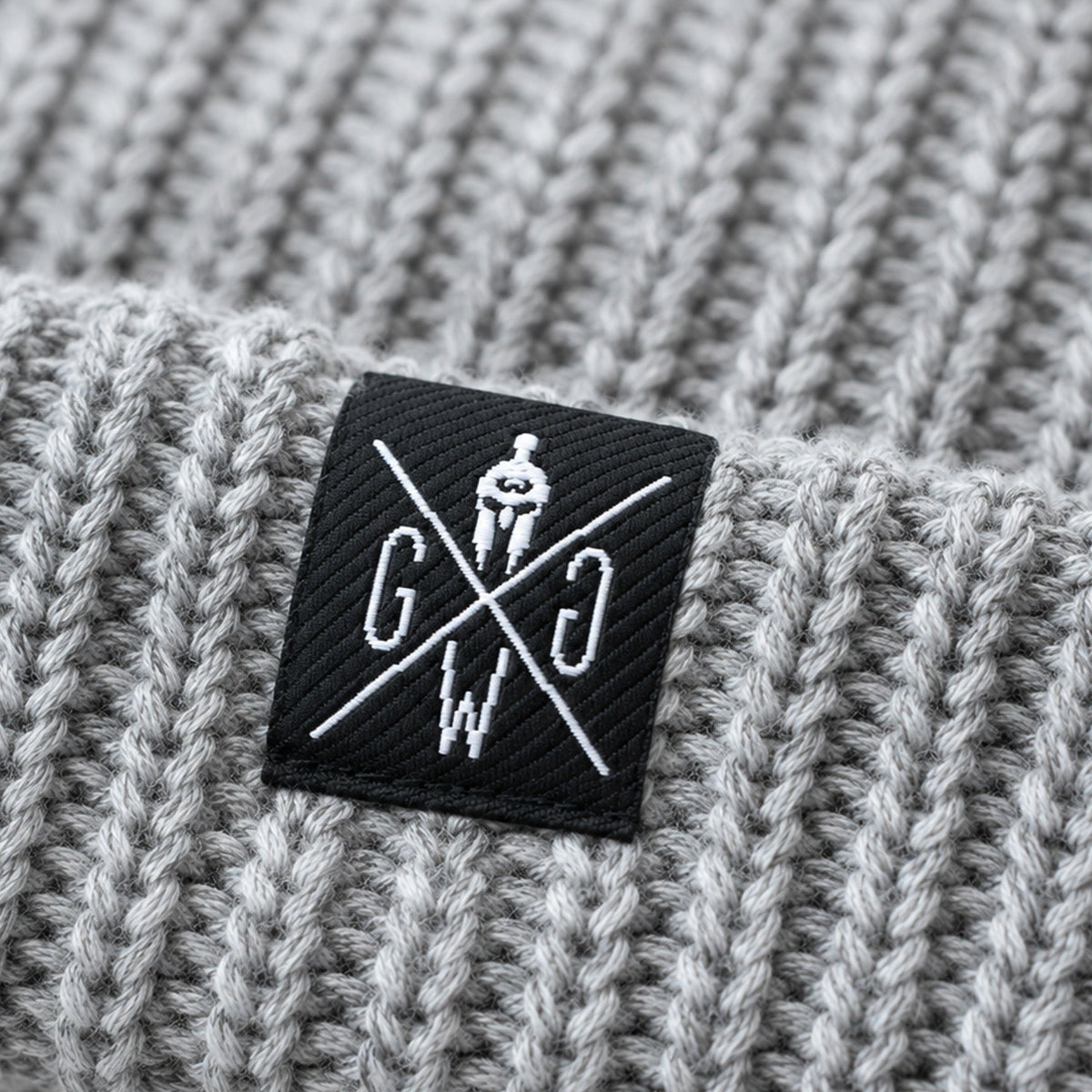 Weblabel auf dem Umschlag der grauen Gym Mütze – Gym Generation Logo in Schwarz-Weiss auf Rippenstrick