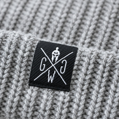Weblabel auf dem Umschlag der grauen Gym Mütze – Gym Generation Logo in Schwarz-Weiss auf Rippenstrick