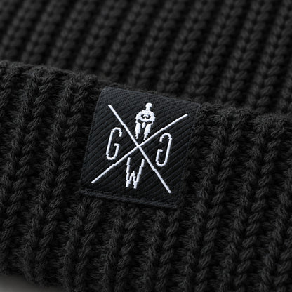 Gym Generation Logo-Patch auf schwarzer Beanie – Nahaufnahme der weissen Stickerei mit Spartaner-Helm auf grobem Rippstrick der Atlantic Mütze