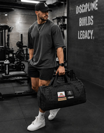 Gym Generation Gym Sporttasche Maverick in Schwarz, getragen von Athlet im Fitnessstudio mit Patches, Laser-Cut-MOLLE und robustem Trainingsdesign