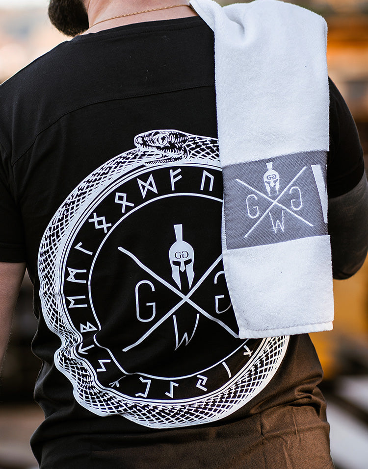 Weisses Fitness-Handtuch mit Gym Generation Logo, über der Schulter eines Sportlers im Outdoor-Workout.