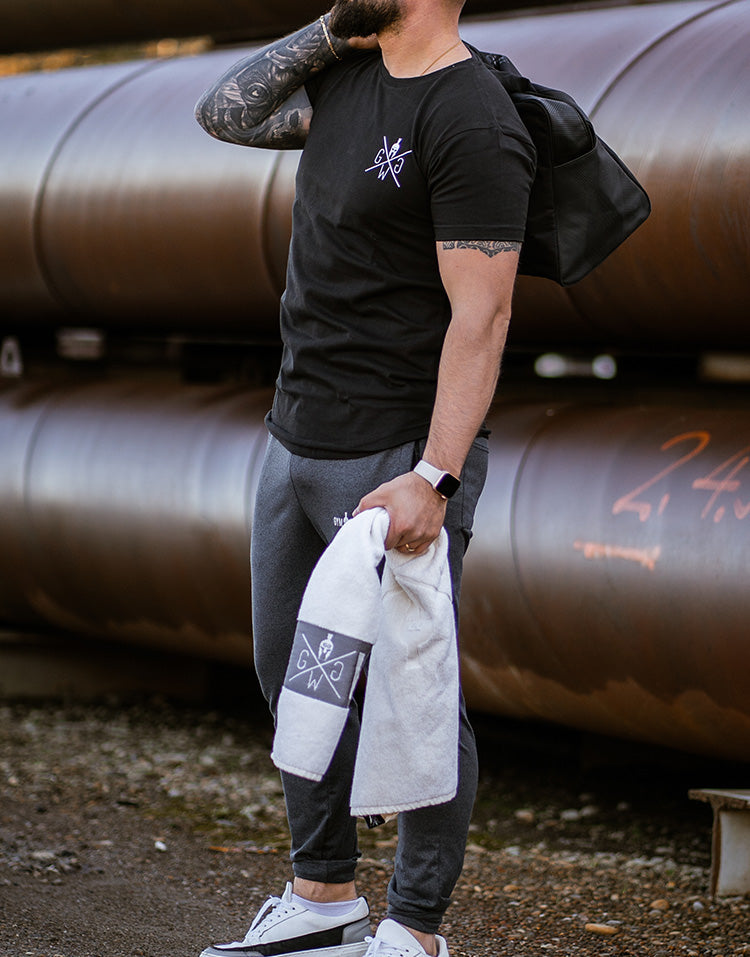 Weisses Gym-Handtuch mit Gym Generation Logo, von Sportler nach dem Training im Outdoor-Fitness-Umfeld gehalten.