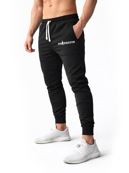 Schwarze Herren Sporthose von Gym Generation am Model in schräger Frontansicht – mit weißem Kordelzug, seitlicher Tasche und schmal zulaufendem Bein