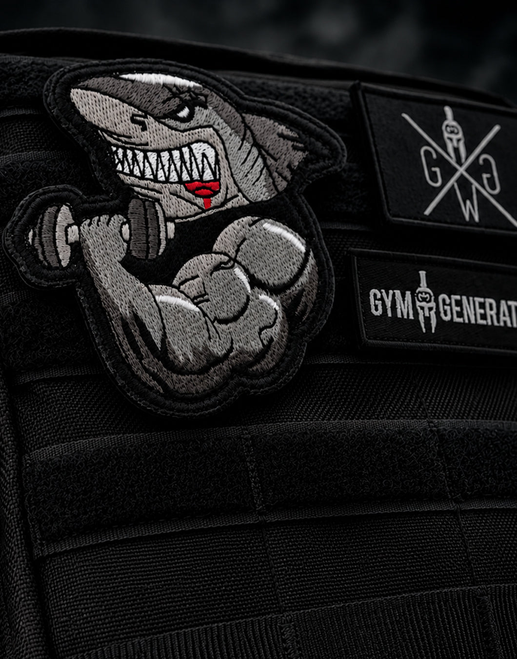 Muscle Shark Patch von Gym Generation am schwarzen MOLLE-Rucksack, gestickter Hai mit Kurzhantel auf Klettpanel