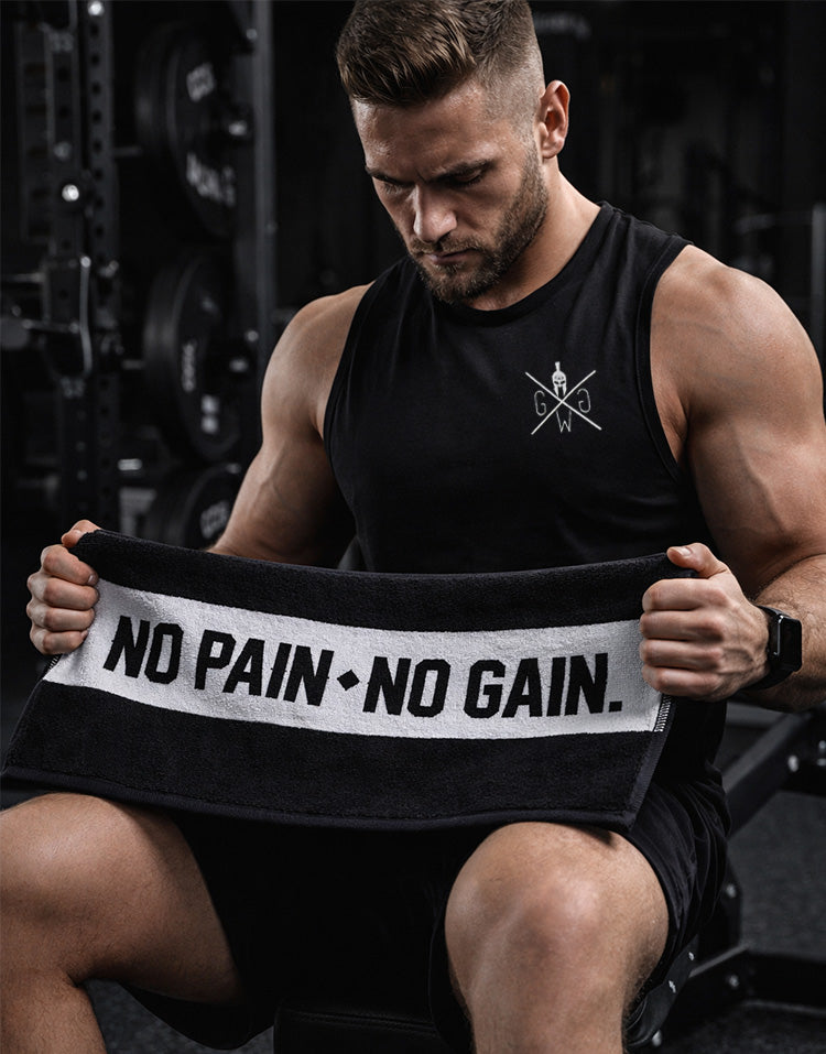 Athlet im Fitnessstudio hält schwarzes No Pain No Gain Fitness Handtuch von Gym Generation – hochwertiges Sporthandtuch für intensives Krafttraining