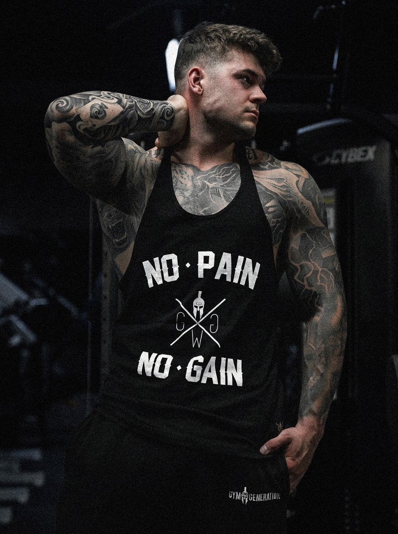 Muskulöser Mann in einem schwarzen Tanktop mit der Aufschrift No Pain No Gain und Gym Generation Logo in einem Fitnessstudio mit tätowierten Armen und athletischer Pose