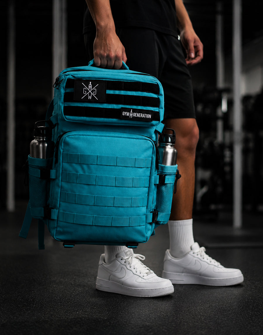 Gym Generation Fitness Rucksack Adventurer in Surf Blue, von Athlet im Gym getragen mit MOLLE-System, Patches und Flaschenfächern