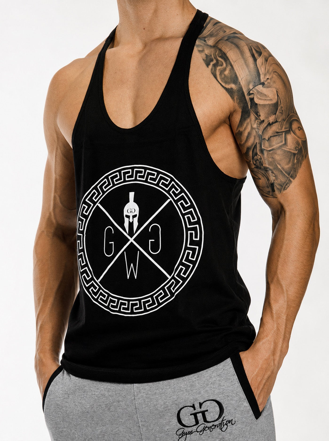 Gym Generation Spartan Stringer in Schwarz mit weissem Print – Spartaner-Helm mit gekreuzten Linien und GGW-Buchstaben im griechischen Mäander-Kreis, ärmelloses Muskelshirt für Herren im Racerback-Schnitt