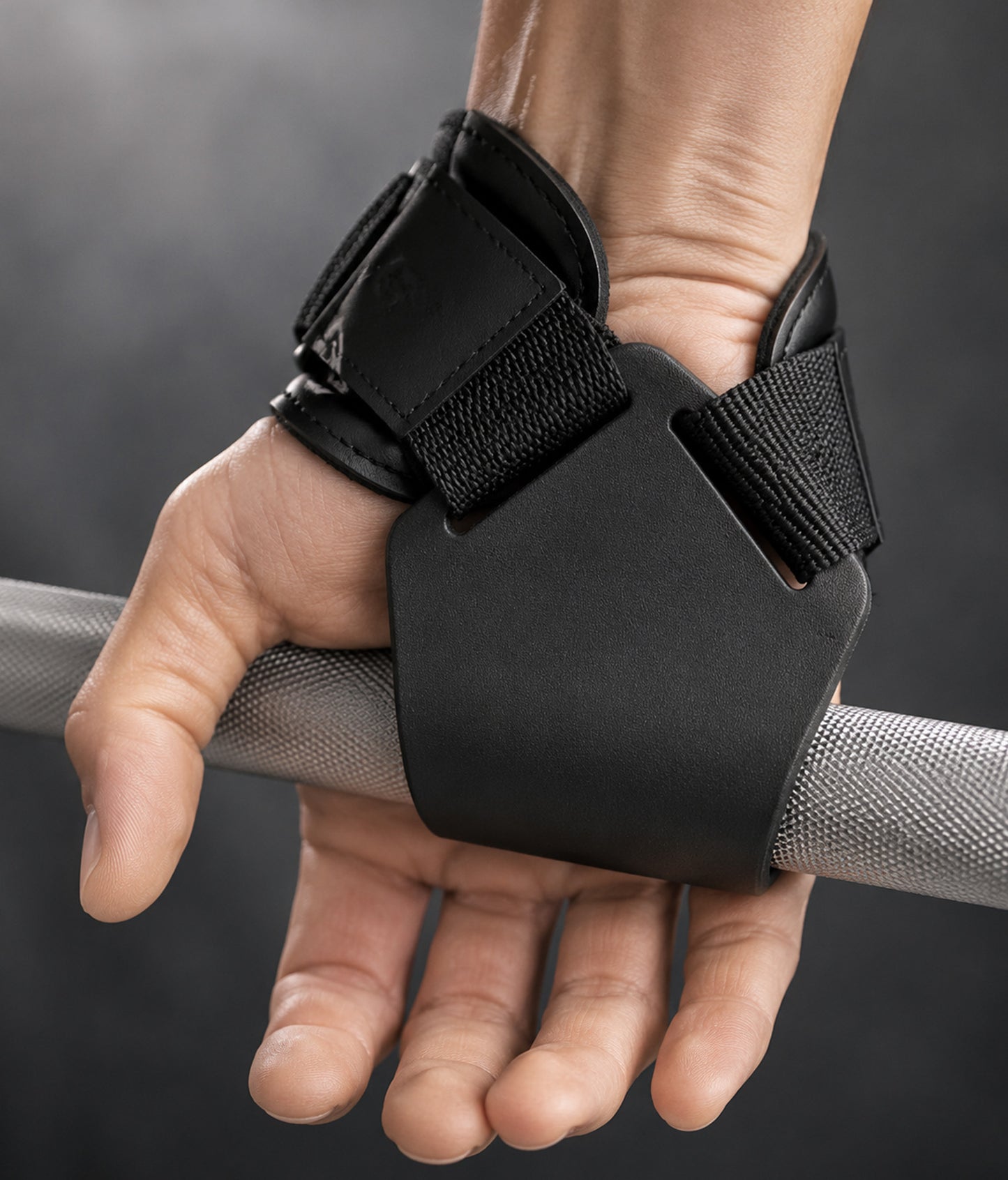 Zughilfen mit Stahlhaken im Einsatz an der Langhantel – Hand mit schwarzer Handgelenkbandage und Klettverschluss von Gym Generation beim Krafttraining im Gym
