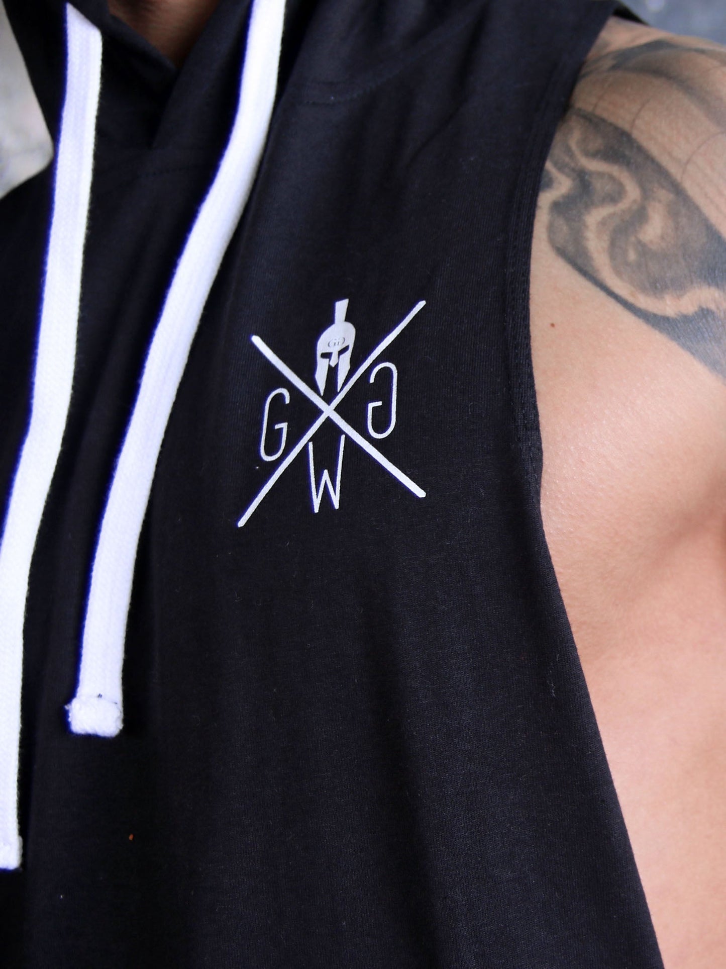 Close-up of the Gym Generation logo on a black hoodie tank top with white drawstrings, highlighting the detailed design and premium quality, ideal for fitness and casual wear.