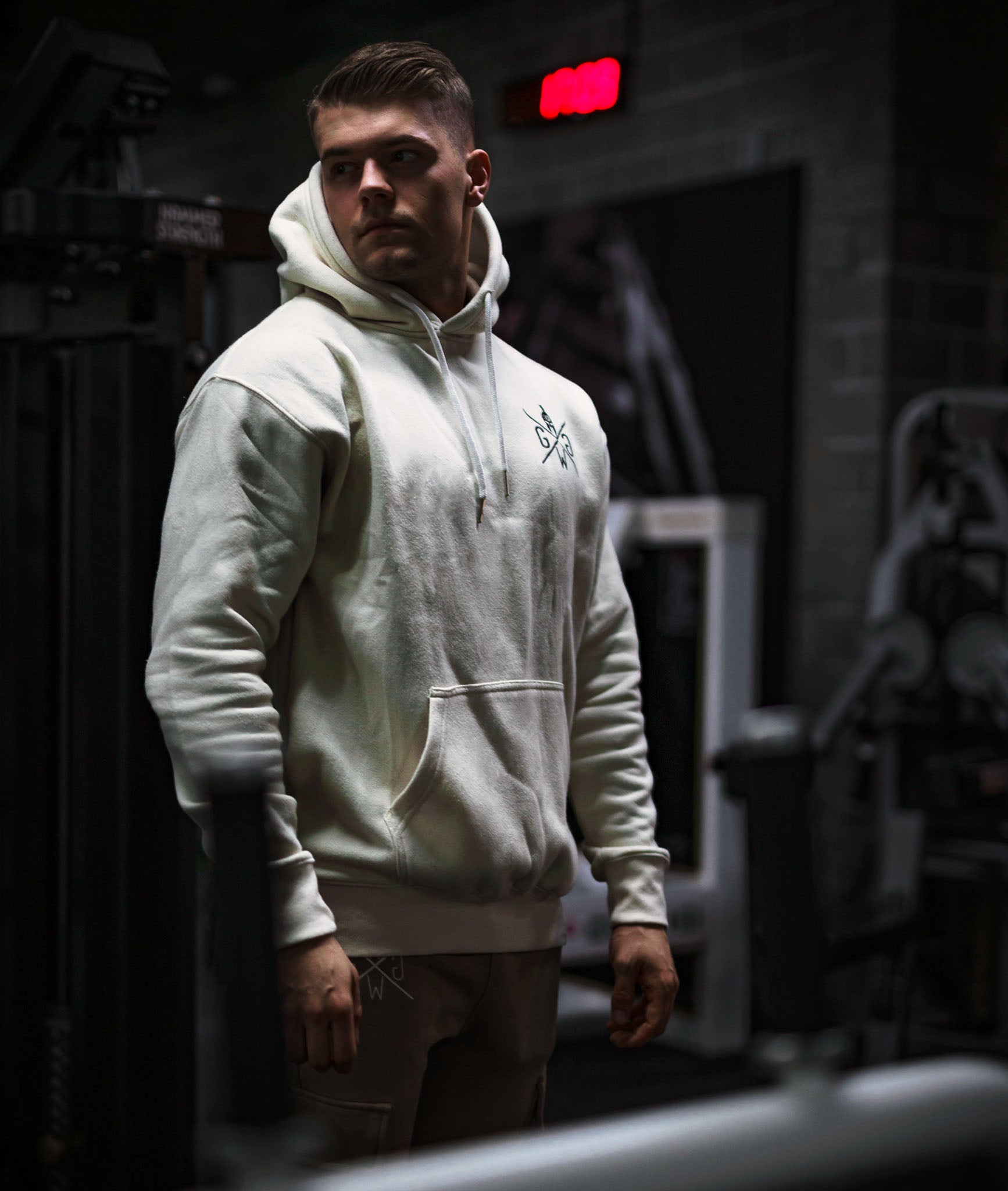 Gym Hoodie Off-White für Herren – Bequemer Kapuzenpullover mit Kängurutasche und Spartaner-Logo, ideal für Fitness und Freizeit.