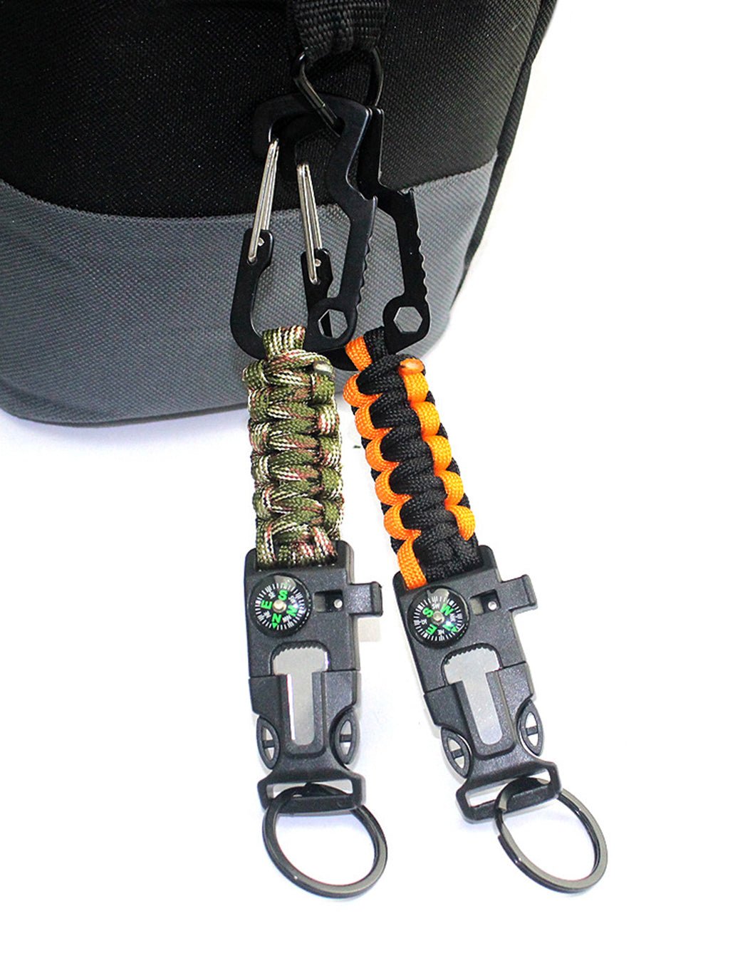 Gym Generation multi-tool keychains clipped to a bag handle – carabiner hooked on, buckle with compass, fire starter and whistle, key ring below