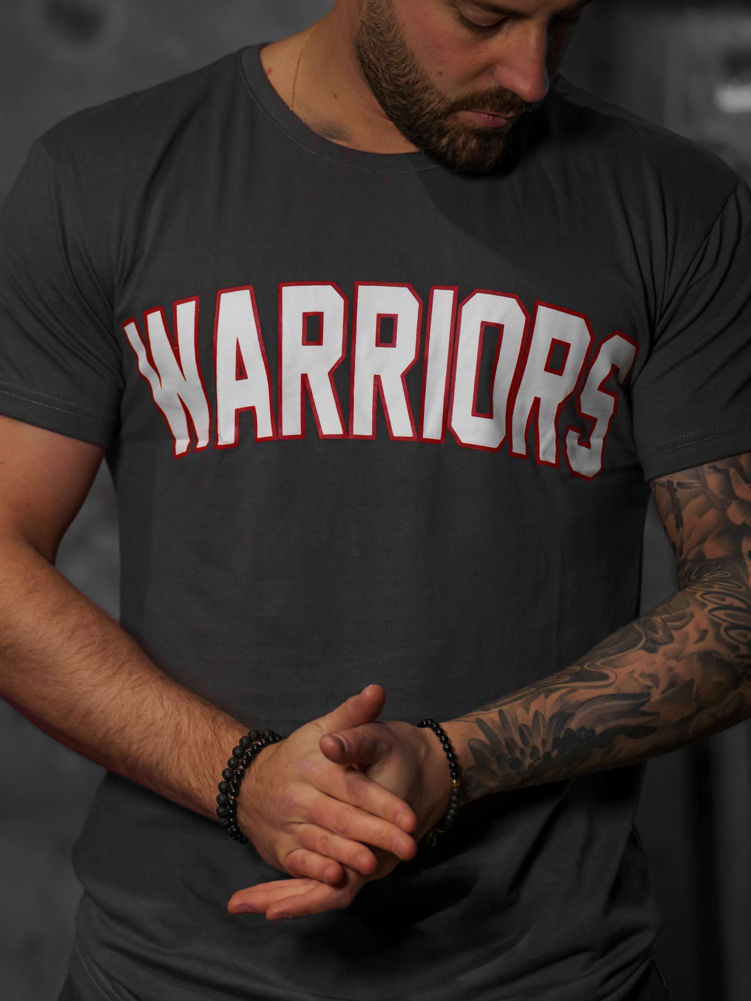 Dunkelgraues Warriors T-Shirt – urbaner Look mit kraftvollem roten Schriftzug, perfekte Passform und hohe Qualität, geeignet für Sport und Freizeit.