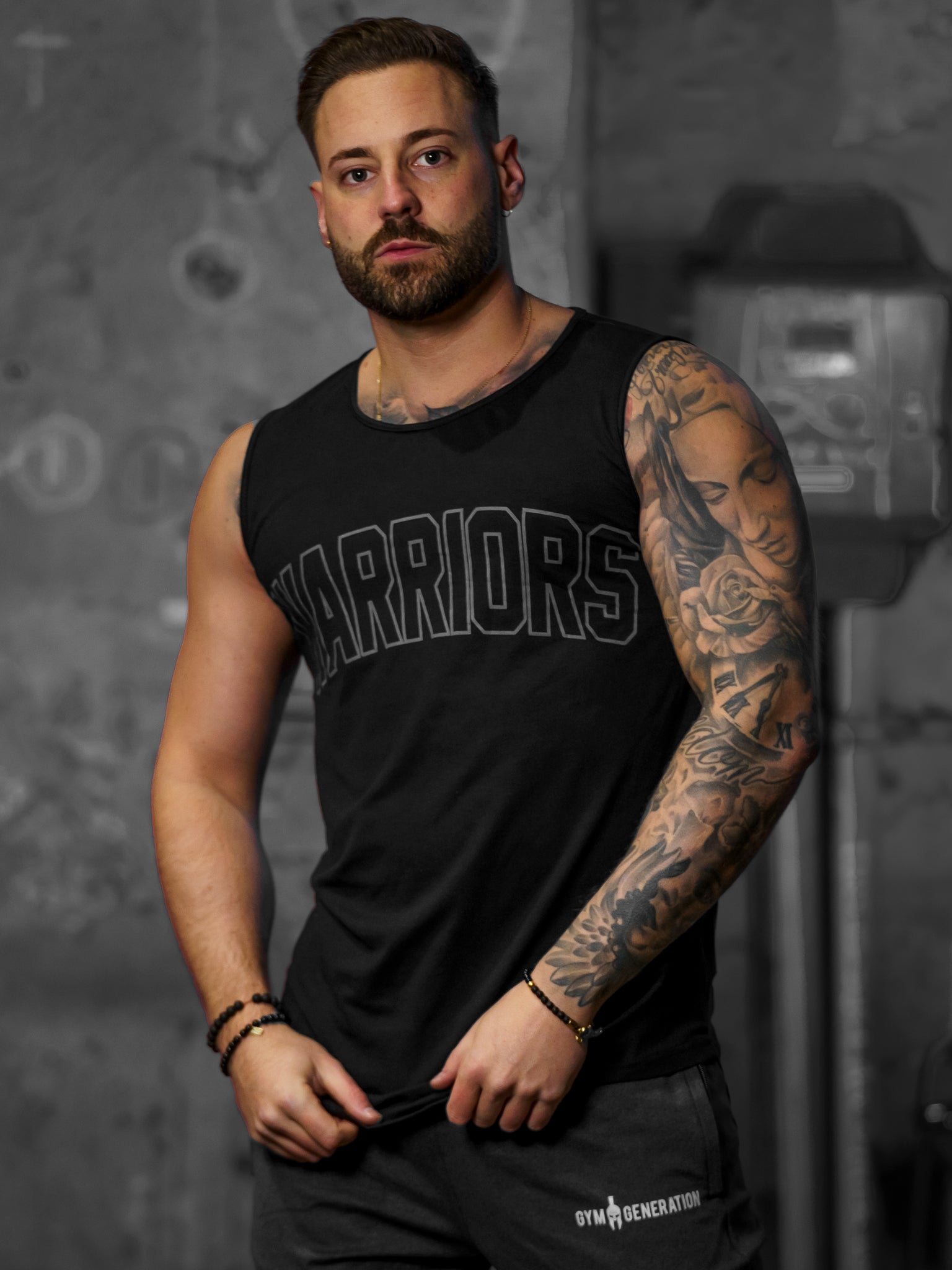 Warriors Tank Top Schwarz von Gym Generation – minimalistisches und kraftvolles ärmelloses Shirt mit Warriors-Print auf der Brust und Spartaner-Logo auf dem Rücken, ideal für Fitness und Freizeit.